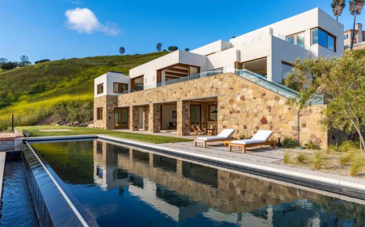 Murphy Way Estate τη λένε και επιβλέπει τον Ειρηνικό Ωκεανό, όσο κι αν θέλει να φέρνει σε μεσογειακή κατοικία. Η θηριώδης 900 τ.μ. έπαυλη στρογγυλοκάθεται σε ιδιωτικό χώρο 14 στρεμμάτων, στον οποίο μεταφέρθηκαν και φυτεύτηκαν ακόμα και ελαιόδεντρα, για μια ακόμα αυθεντικότερη μεσογειακή εμπειρία. Η μεσογειακή αισθητική κυριαρχεί και στο εσωτερικό με τις 6 κρεβατοκάμαρες και τα 8 μπάνια, με πρόδηλα ρουστίκ νότες που δημιουργούν τα ρετρό ξύλινα δοκάρια των 300 ετών. Το τριώροφο μεγαλούργημα του Μαλιμπού φιλοξενεί πισίνες, σάουνες, σπα και ειδικούς χώρους για γιόγκα, πλάι στο θέατρο, τα κελάρια, το γυμναστήριο και το ευρύχωρο γκαράζ των 20 θέσεων. Και βέβαια προσφέρει πανοραμική θέα στη θάλασσα, φέρνοντας τη Μεσόγειο σε μια από τις ακριβότερες περιοχές της Καλιφόρνια. Η βίλα βγήκε πρόσφατα προς πώληση με τιμή στα 14,95 εκατ. ευρώ (16,9 εκατ. δολάρια)… Murphy Way Estate